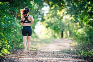 jeune femme de remise en forme qui court sur une route rurale. femme sportive en cours d'exécution. photo