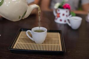 verser du thé vert chaud dans une tasse. photo