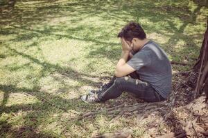 triste jeune homme assis dans le parc photo