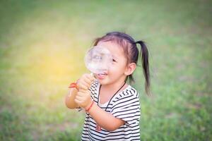 asiatique peu fille est en utilisant grossissant verre à jouer dans le parc.sstkhome photo