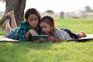 deux Jeune les filles mensonge sur le pelouse à la recherche à leur Téléphone (s, été, d'or heure, le coucher du soleil. sstkhome photo