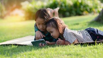 deux Jeune les filles mensonge sur le pelouse à la recherche à leur Téléphone (s, été, d'or heure, le coucher du soleil. sstkhome photo