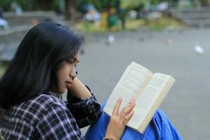 content conscient Jeune asiatique femme Université étudiant en train de lire une livre dans le parc, éducation concept photo