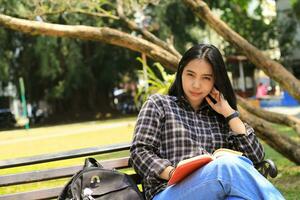 content conscient Jeune asiatique femme Université étudiant en train de lire une livre dans le parc, éducation concept photo