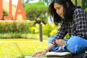 content Jeune asiatique femme concentré en utilisant portable travail à distance et navigation dans social médias dans confortable en plein air espace photo