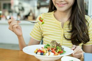 régime et suivre un régime, prendre plaisir manger. en bonne santé femme tenir salade nourriture et sentiment heureux. beauté svelte femelle corps atteint poids perte objectif pour en bonne santé vie, fou à propos minceur, mince taille, nutritionniste. photo