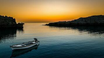 solitaire bateau dans le coucher du soleil lever du soleil sur une mer dans Lindos baie, Rhodes, Grèce photo