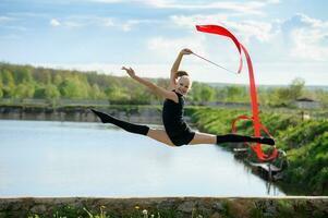 gymnaste fille Faire jambe fendue dans une sauter avec ruban photo