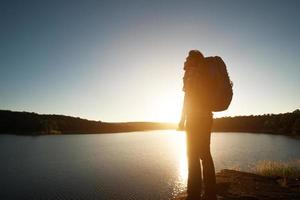 silhouette d'homme randonneur avec sac à dos en montagne paysage coucher de soleil. photo
