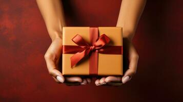 femelle mains en portant une cadeau boîte avec une rouge arc sur une rouge Contexte photo