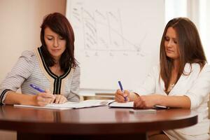 deux femmes prenant des notes lors d'une présentation commerciale photo