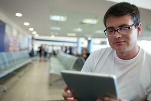 homme en train de lire sur tablette PC tandis que attendre à le aéroport photo