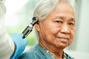 oto-rhino-laryngologiste ou ent médecin médecin examiner Sénior patient oreille avec otoscope, audition perte problème. photo