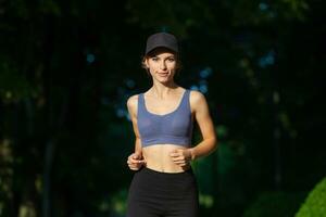 sportif Jeune femme dans tenue de sport Faire élongation des exercices en plein air. portrait de une Jeune fille Faire sport dans le parc. photo