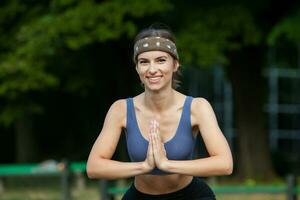 sportif Jeune femme dans tenue de sport Faire élongation des exercices en plein air. portrait de une Jeune fille Faire sport dans le parc. photo