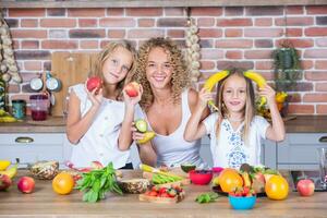 mère et filles cuisine ensemble dans le cuisine. en bonne santé nourriture concept. portrait de content famille avec Frais smoothies. photo