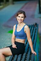 sportif Jeune femme dans tenue de sport Faire élongation des exercices en plein air. portrait de une Jeune fille Faire sport dans le parc. photo