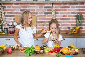 deux peu les filles dans le cuisine avec Frais des légumes. en bonne santé nourriture concept. content sœurs. photo