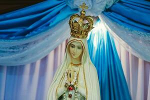 statue de le vierge Marie et le couronne sur le Contexte de une bleu rideau photo