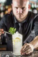professionnel barman fabrication alcoolique cocktail boisson avec des fruits sucre et herbes photo