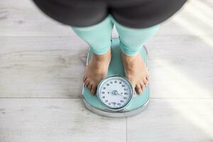 un obèse femme des stands sur une échelle et pèse plus que 100 kilogrammes photo