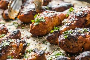 grillé poulet jambes un barbecue avec épices herbes et sésame sur cuit papier. rôti la volaille repas dans rôtissoire plat photo