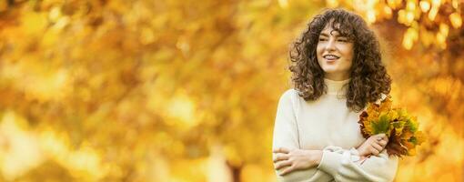 Jeune femme avec l'automne bouquet de érable feuilles. fille avec une dentaire un appareil dentaire et frisé cheveux photo