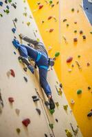 grimpeur sur mur.jeune homme pratiquant Roche escalade sur une Roche mur à l'intérieur photo