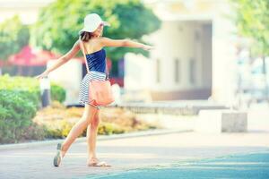 magnifique mignonne Jeune fille dansant sur le rue de bonheur.mignon content fille dans été vêtements dansant dans le Soleil photo