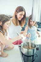 maman avec deux Jeune jumeaux filles dans le cuisine cuisine spaghetti photo