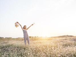 sexy belle femme debout dans un champ de fleurs et tenant son chapeau photo