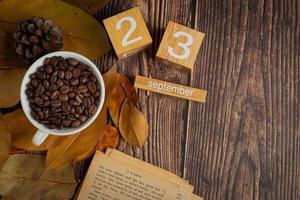 une tasse de café posée sur un livre et un calendrier avec des feuilles sèches. photo