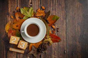 une tasse de café posée sur le sol et un calendrier avec des feuilles sèches. photo