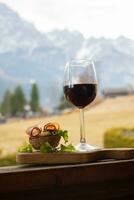 une verre de rouge du vin et une sandwich sur une en bois planche photo