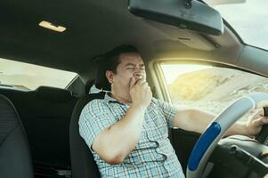 vue de une somnolent chauffeur dans le sien auto. fatigué chauffeur bâillement dans le voiture, concept de homme bâillement tandis que conduite. une somnolent chauffeur à le roue, une fatigué la personne tandis que conduite photo