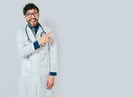 Jeune médecin montrer du doigt une promotion avec doigt. content médecin montrer du doigt à La publicité espace isolé. content médecin montrer du doigt droite avec doigt photo