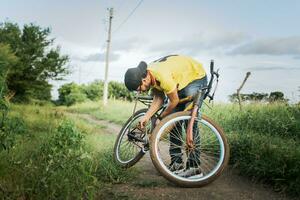 homme dans le campagne réparer le sien vélo, voyageur la personne réparer le sien bicyclette sur le route, homme réparer le sien bicyclette dans le milieu de le route photo