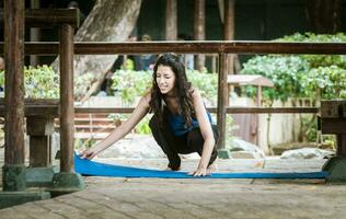 une fille pose en dehors sa yoga tapis, femme diffusion sa yoga tapis en plein air photo