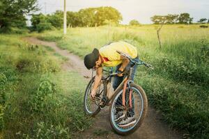 homme réparer le sien bicyclette dans le milieu de le route, homme dans le campagne réparer le sien vélo, voyageur la personne réparer le sien bicyclette sur le route photo