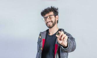 souriant homme en portant bitcoin pièce de monnaie, Beau homme montrant bitcoin pièce de monnaie, la personne en portant bitcoin pièce de monnaie isolé photo