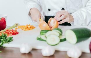 proche en haut de chef femme mains Coupe tomates et légumes, chef mains en train de préparer et Coupe des légumes. chef femme mains Coupe tomates et des légumes photo