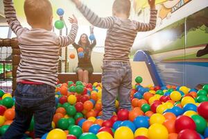 jeune maman jouant avec des enfants dans la piscine avec des boules colorées photo