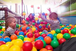 jeune maman jouant avec des enfants dans la piscine avec des boules colorées photo