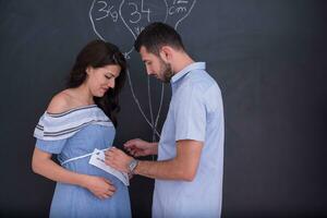 Couple enceinte dessinant leur imagination sur tableau noir photo