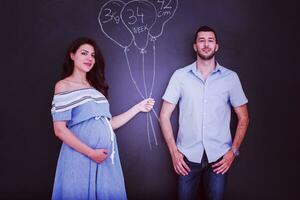 Couple enceinte dessinant leur imagination sur tableau noir photo