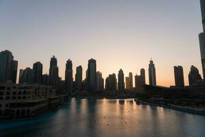 Dubai en chantant fontaines à nuit Lac vue entre grattes ciels. ville horizon dans crépuscule moderne architecture dans Émirats arabes unis Capitale centre ville. photo