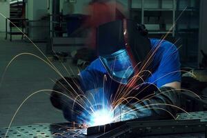 soudeur professionnel de l'industrie lourde travaillant à l'intérieur de l'usine, porte un casque et commence à souder. mise au point sélective photo