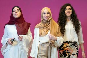 groupe portrait de magnifique musulman femmes deux de leur dans à la mode robe avec hijab isolé sur rose Contexte représentant moderne Islam mode et Ramadan kareem concept photo