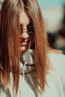 une fille moderne avec des lunettes de soleil marchant dans la rue écoute de la musique dans des écouteurs. photo