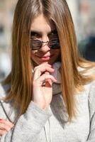 une fille moderne avec des lunettes de soleil marchant dans la rue écoute de la musique dans des écouteurs. photo